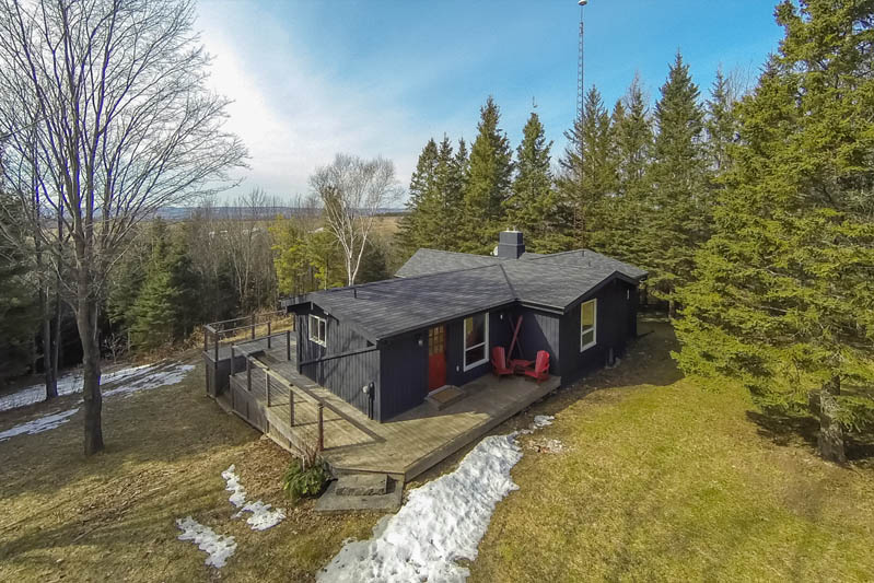 Elevated photo of the front of a small cabin in the woods on a windy day where a drone couldn't fly