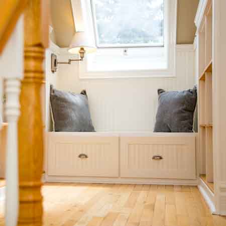 Inviting view of a reading nook at the top of an attic stairway.